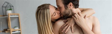 Sexy Blonde Woman With Closed Eyes Kissing Shirtless Man At Home