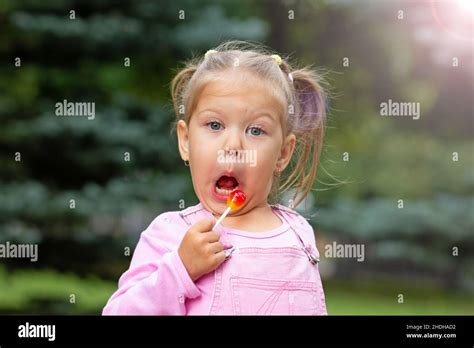 Beautiful child with funny face licking lollipop Stock Photo - Alamy