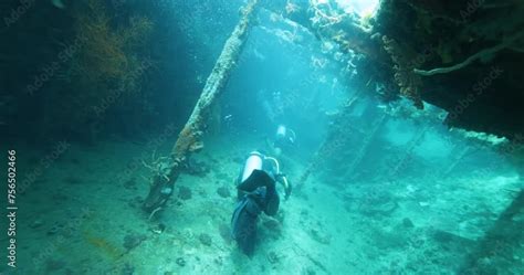 A Group Of Divers Diving Towards A Sunken Ship In The Philippine Sea