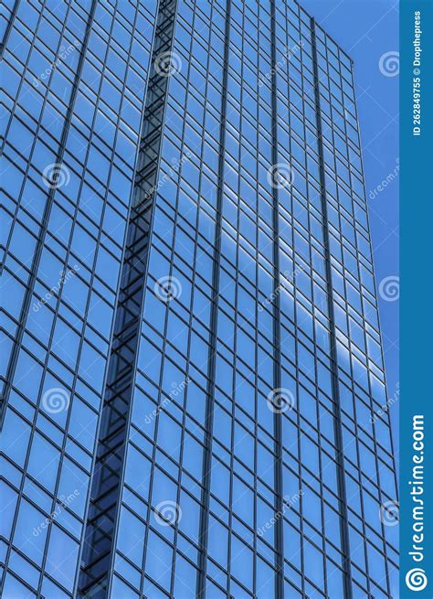 Towering Skyscraper With Glass Windows Facade Reflecting The Clear Blue