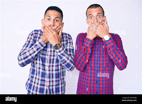 Jeune gay couple de deux hommes portant des vêtements décontractés choqué couvrant la bouche