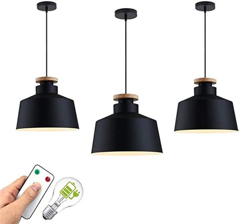 Three Black Pendant Lights With Remote Controls In The Foreground And