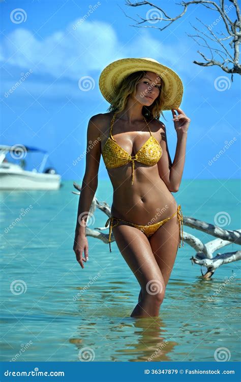 Bikini Model In Straw Hat Posing In Front Of Camera At Tropical Beach