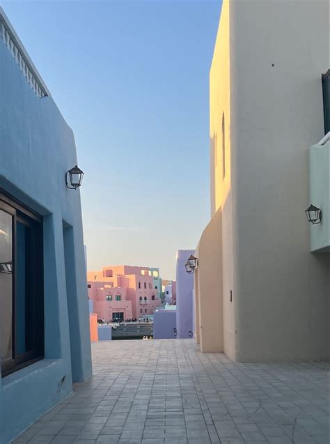 An Alley Way Between Two Buildings With Blue And Pink Walls On Both