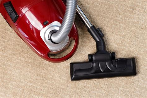 premium photo red vacuum cleaner   beige carpet