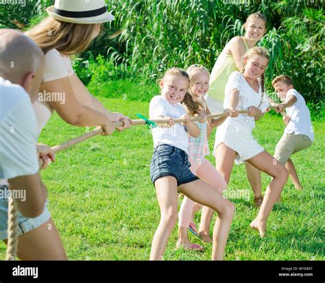 Kids with parents playing tug of war during joint outdoors games on sunny day Stock Photo - Alamy