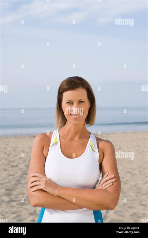 Portrait Of Happy Mature Woman Standing Hands Folded On Beach Stock Photo Alamy