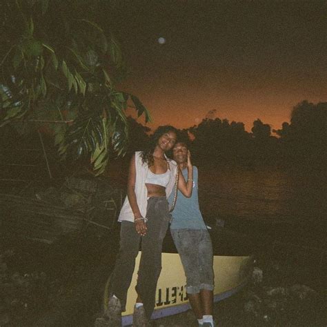 Two People Standing Next To Each Other In Front Of A Boat On The Water