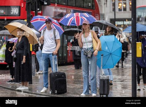 Commuters And Tourists Brave The Torrential Summer Rain Showers On