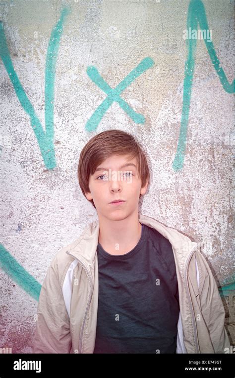 Boy Standing In Front Of Brick Wall With Graffiti Hi Res Stock