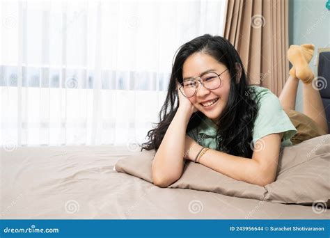 Beautiful Glasses Asian Woman Is Lying On Her Stomach And Looks At