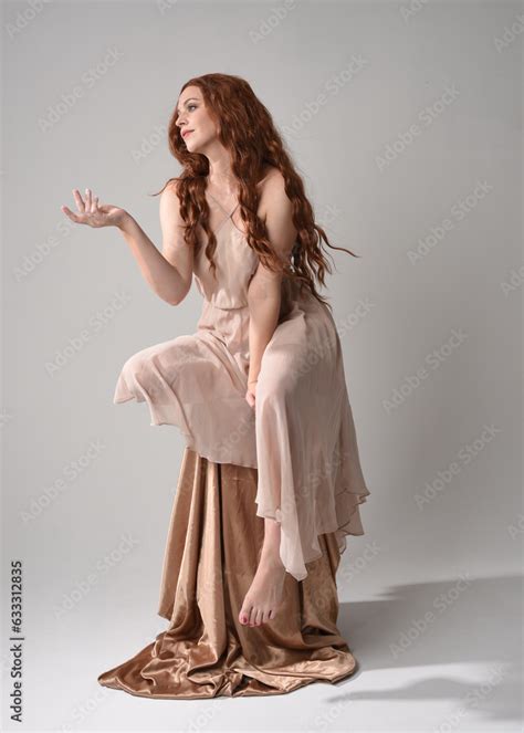 Full Length Portrait Of Beautiful Female Model With Long Brunette Hair Wearing A Creamy Pink