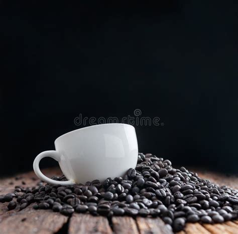 Close Up Shot Of White Ceramic Cup On Pile Of Dark Roasted Coffee Bean