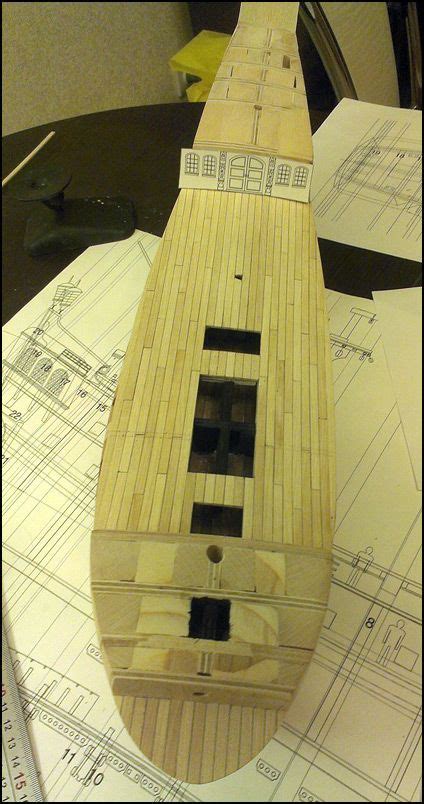 A Wooden Model Of A Boat Sitting On Top Of Blueprints