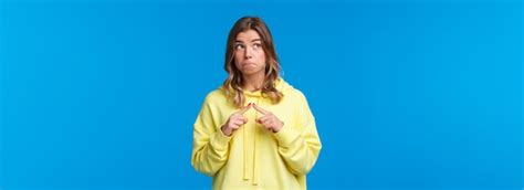Timide et stupide fille blonde kawaii en sweat à capuche jaune étant modeste embarrassé dire je