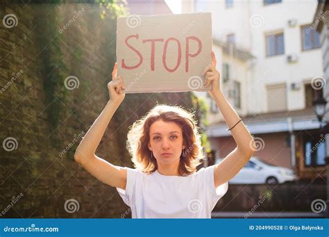 Young Protesting Woman In White Shirt And Jeans Holds Protest Sign