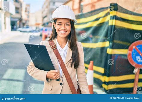 Joven Arquitecta Latina Sonriendo Feliz Sosteniendo Planos En La Ciudad Imagen De Archivo