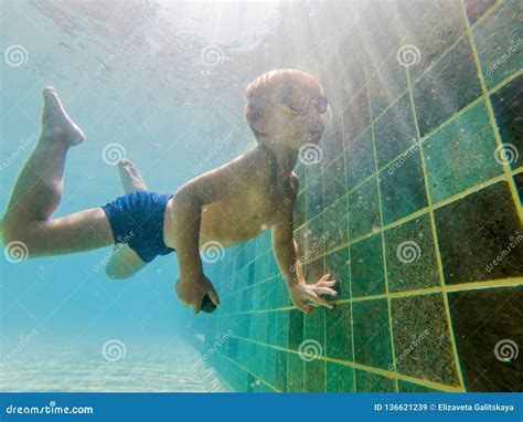 A Child Boy is Swimming Underwater in a Pool, Smiling and Holding Breath, with Swimming Glasses ...