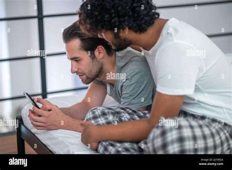 Biracial Gay Couple Staring At The Smartphone Screen Stock Photo Alamy