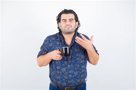 Free Photo Mature Man In Shirt Holding Cup While Smelling Tea And Looking Delighted Front View