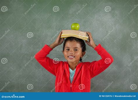 Libros Y Manzana De Equilibrio De La Chica Joven En Su Cabeza Foto De