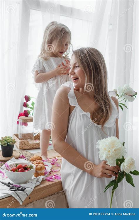 Une Petite Fille Blonde Avec Sa Mère Sur Un Plan De Cuisine Décoré De Pivoines Le Concept De