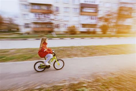 Jonge Blonde Meid Met Een Rode Jas Op De Fiets Stock Afbeelding Image Of Park Vrolijk