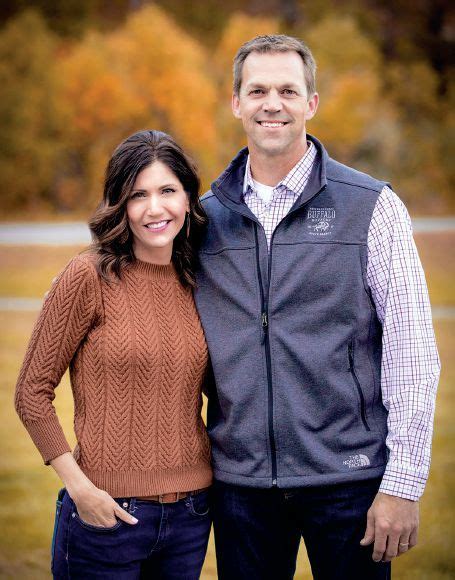 a man and woman standing next to each other in front of some trees with ...