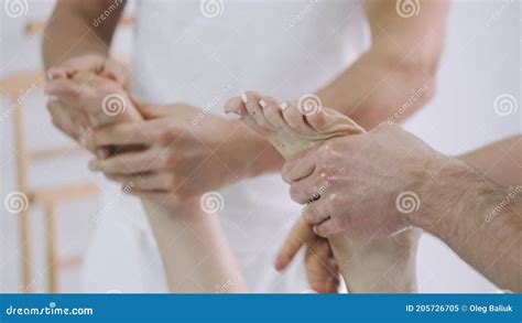 Two Male Massage Therapists Doing Massage Of The Legs Of A Young Girl