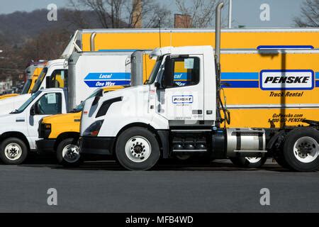 A logo sign and rental trucks outside of a facility occupied by Penske ...