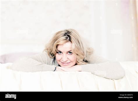 Beautiful Blonde Woman With Long Hair Smiling And Lying On White Bed Stock Photo Alamy