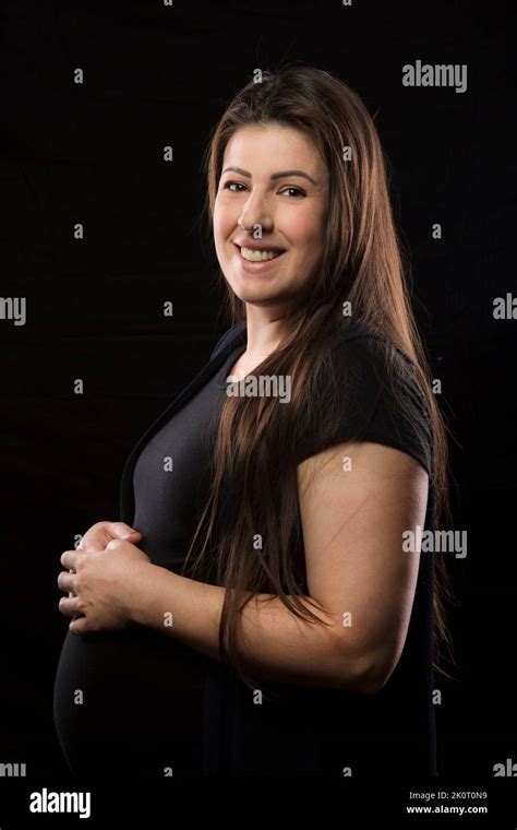 Une Jeune Femme Brunette Aux Derniers Stades De La Grossesse Sourit Et Pose Avec Sa Bosse De