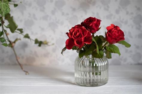 Premium Photo A Vase Of Red Roses Sits On A White Table