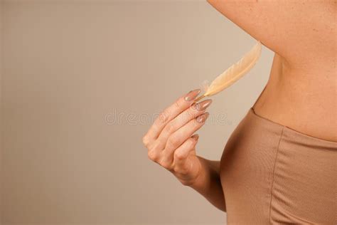 In A Nude Colored Top A Girl Gently Touches Her Underarms With A Feather This Calm And