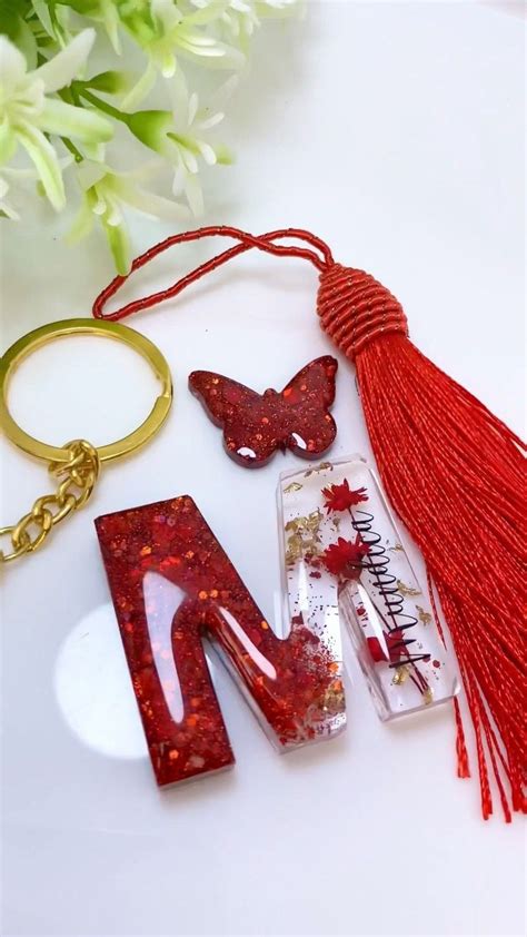 The Letter M Is Decorated With Red Beads And Tassels