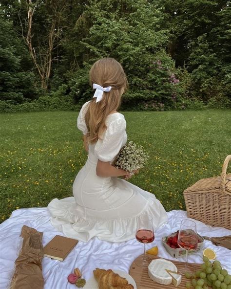 A Woman Sitting At A Picnic Table With Food And Wine In Front Of Her