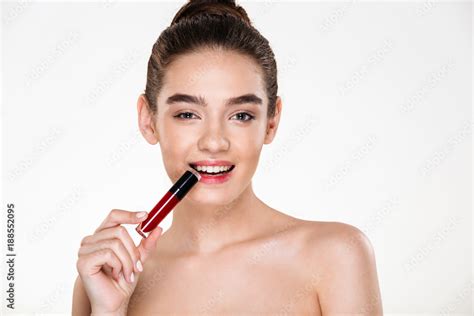 Close Up Studio Portrait Of Flirting Brunette Woman With Hair In Bun Holding Lipstick In Mouth