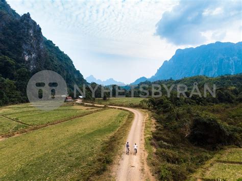 Aerial Tourist Couple Riding Mountain Bike On Dirt Road In Scenic