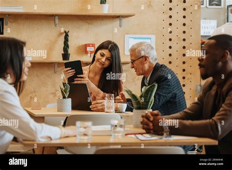 Female Brunette Employee Holding A Tablet Working With Her Senior Male Colleague S