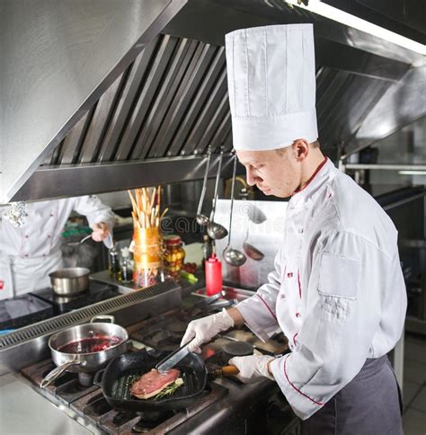 Cocinero En Cocina Del Restaurante En La Estufa Con La Cacerola