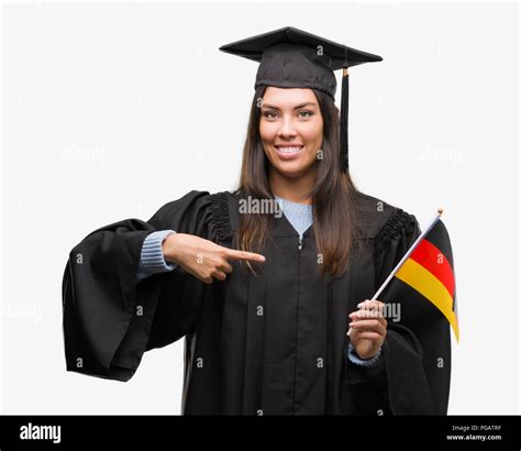 Young Hispanic Woman Wearing Graduated Uniform Holding Flag Of Germany