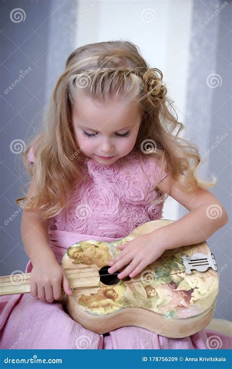 Jolie Petite Fille Blonde En Robe Rose Avec Des Boucles Avec Une