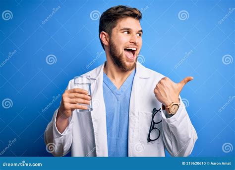 Junge Blonde Arzt Mann Mit Bart Und Blauen Augen Tragen Mantel Trinkglas Von Wasser Zeigen Und