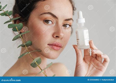 Half Naked Brunette Woman Showing Face Serum And Eucalyptus Stock Photo