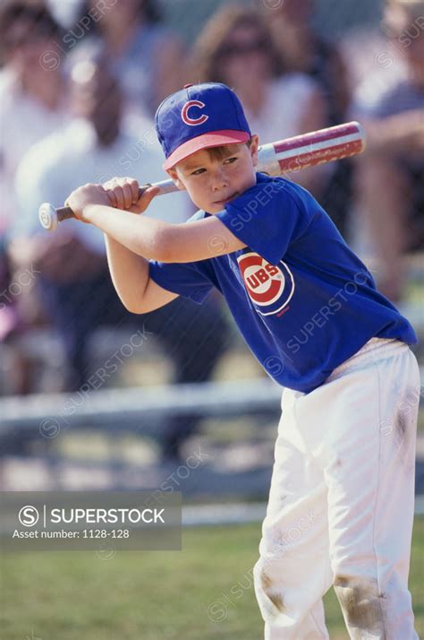 Boy swinging a baseball bat on a field - SuperStock