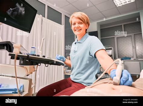 Sonographer In Sterile Gloves Examining Patient With Ultrasound Scanner