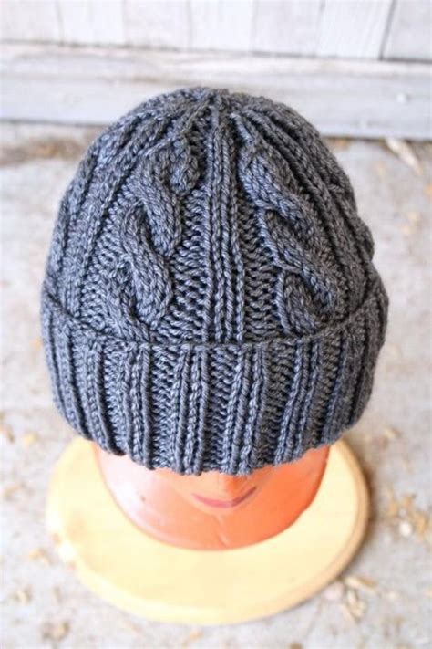 a gray knitted hat sitting on top of a wooden stand next to a door