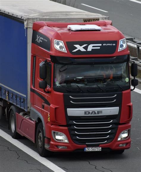 A Red And Black Semi Truck Driving Down A Street Next To A Blue Sign