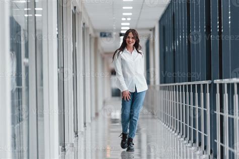 Brunette In White Shirt Walks Indoors In Modern Airport Or Hallway At Daytime 15249342 Stock
