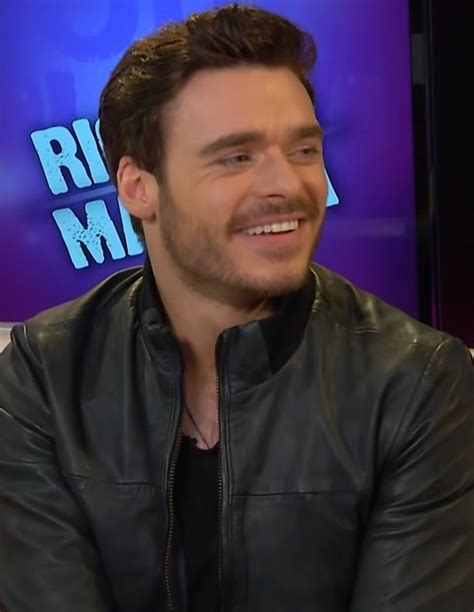 A Man In A Black Leather Jacket Is Smiling And Looking At The Camera